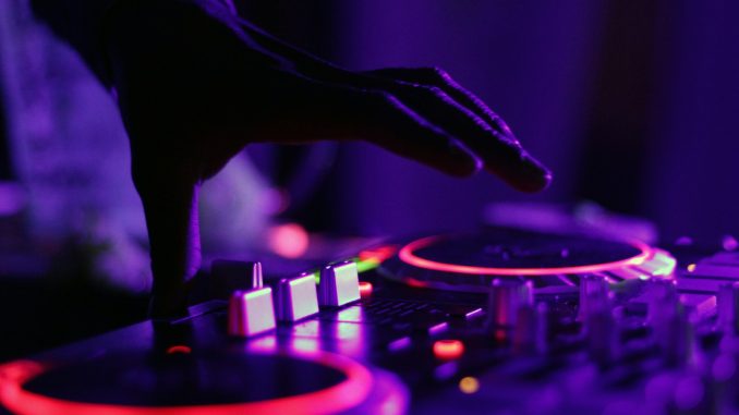 Photo by Marcela Laskoski selective focus silhouette photography of man playing red-lighted DJ terminal