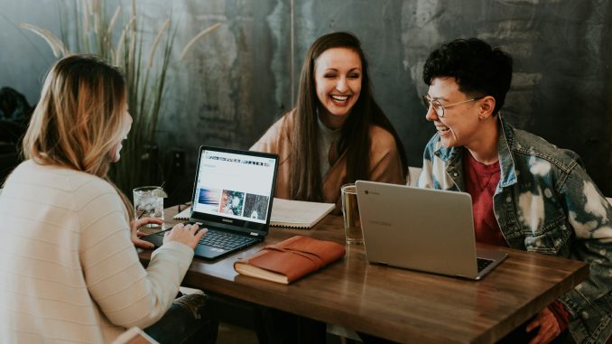 Photo by Brooke Cagle three people sitting in front of table laughing together