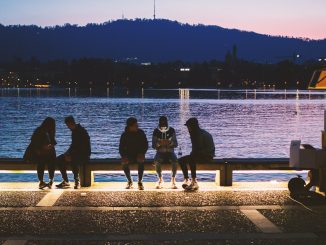 five people sitting near body of water