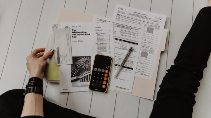 Photo by Kelly Sikkema person holding paper near pen and calculator
