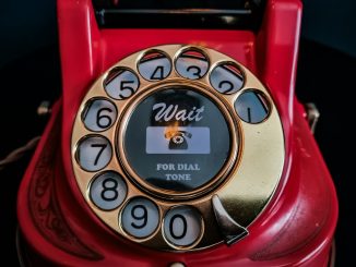 an old red rotary telephone with a dial on it