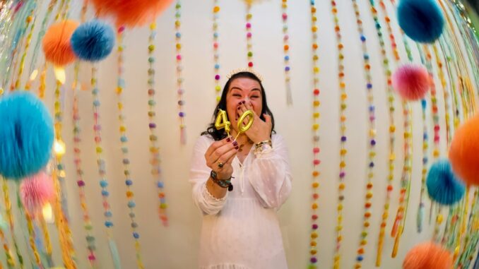Woman celebrating with "40" balloons and colorful decorations